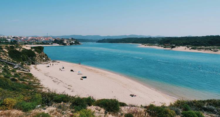 Vue sur la rivière avec berges sablonneuses et village perché.