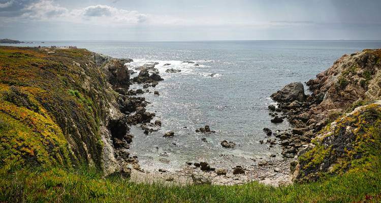 Crique au bord de la falaise avec des rivages rocheux et une vue lointaine sur la mer.