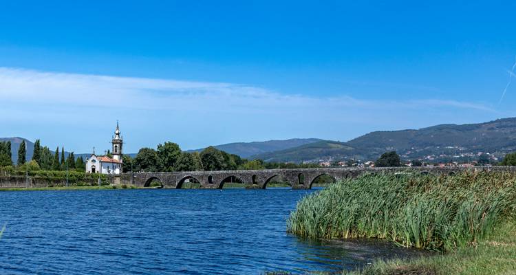 Pont s'étendant sur une large rivière avec vue sur les montagnes.