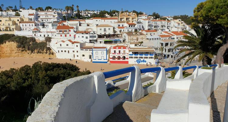 Vue aérienne d'un village côtier avec des bâtiments blancs sur une falaise.