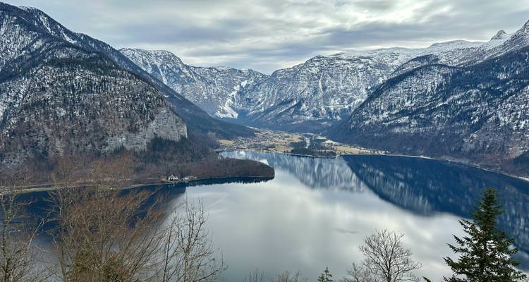 Bergachtig landschap met reflecterend meer en bewolkte luchten.