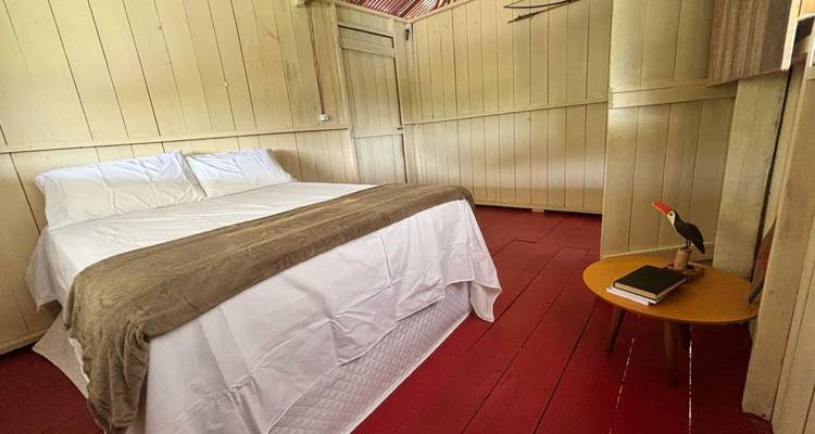 Intérieur d'une pièce rustique avec un lit, des murs en bois et un mobilier basique.