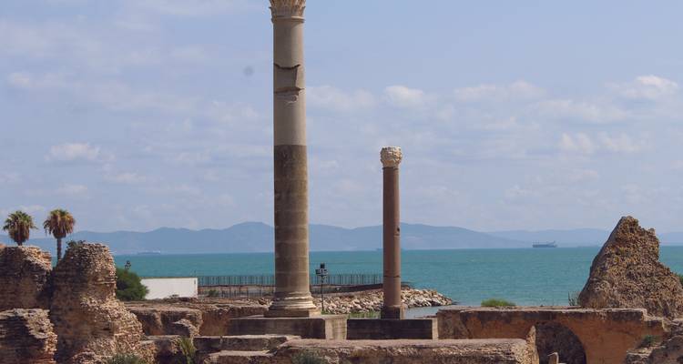Ruins with columns set against a sea backdrop.