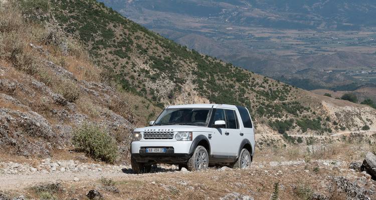 Véhicule tout-terrain sur un sentier de terre montagneux.