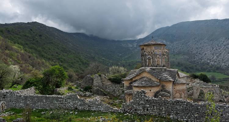Vieille église en pierre sur fond de montagnes.
