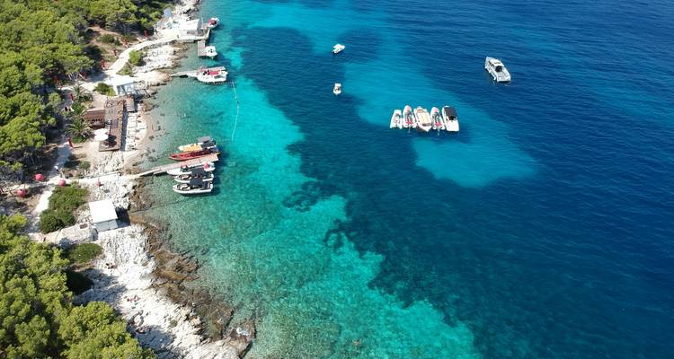 Luchtfoto van een kustlandschap met boten en turquoise water.