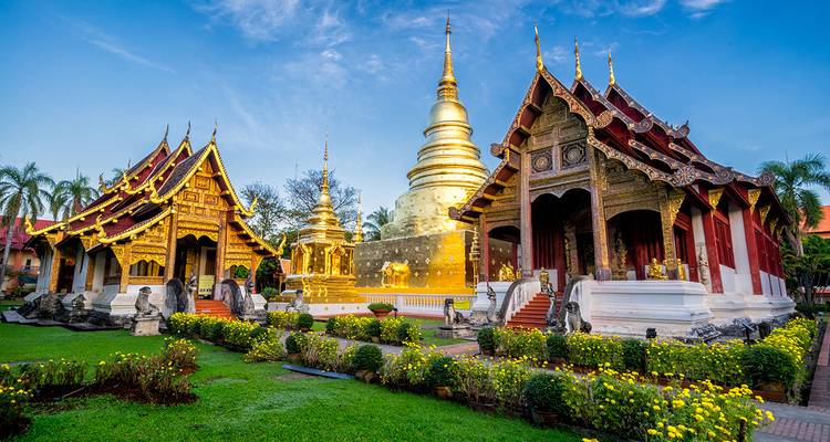 Complexe de temples bouddhistes ornés sous un ciel bleu.