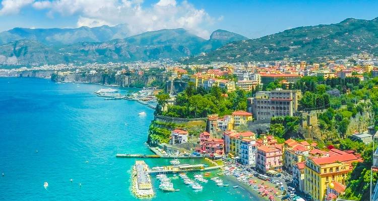 Vue aérienne ensoleillée de la ville côtière colorée de Sorrente et de sa marina contre les eaux bleu éclatant.