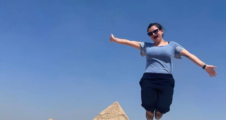 Personne sautant joyeusement avec une pyramide en arrière-plan.