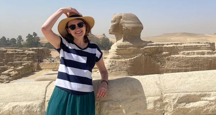 Personne souriante à côté du Sphinx avec un ciel lumineux.