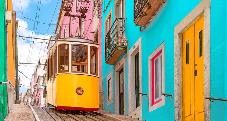 Kleurrijke tram in een smalle straat omzoomd met levendige gebouwen.