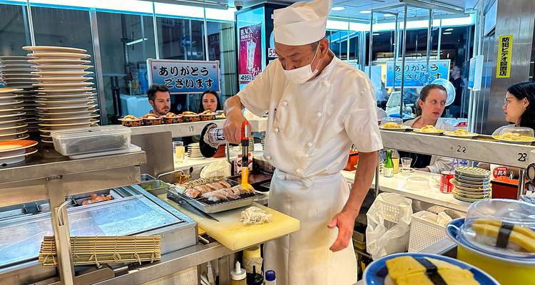 Chef preparing sushi in a bustling restaurant.