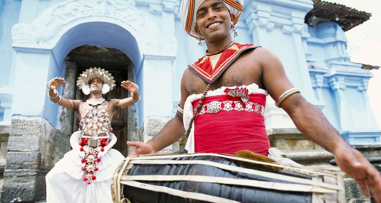 Bailarines con atuendo tradicional de Sri Lanka actuando fuera de un edificio histórico.