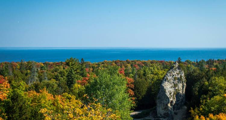 Rock formation standing tall in a colorful foliage setting.