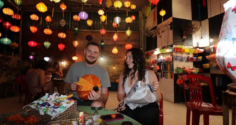 Couple fabriquant des lanternes dans une pièce remplie de lanternes suspendues.