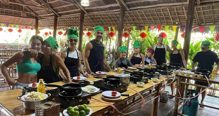 Cours de cuisine en groupe avec des personnes portant des tabliers et des toques.