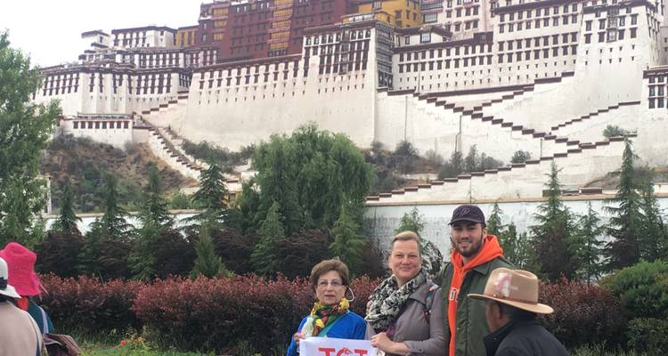 Groupe de personnes posant devant un grand palais historique aux détails colorés.