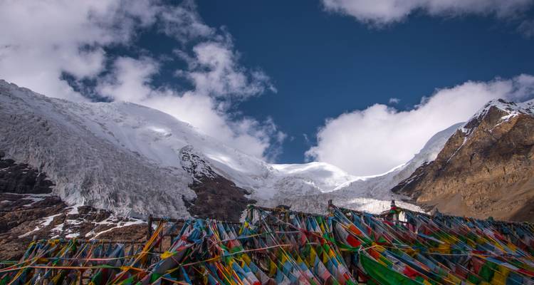 Paysage montagneux avec des drapeaux de prière colorés au premier plan.