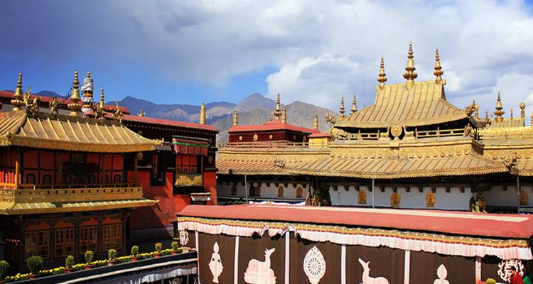 Complexe de temple élaboré avec des toits aux accents dorés et des montagnes en arrière-plan.