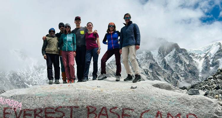 Un groupe de randonneurs posant au camp de base de l'Everest avec des montagnes en arrière-plan.