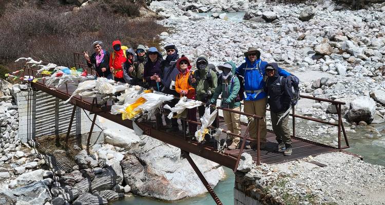 Un groupe de randonneurs sur un pont au-dessus d'un ruisseau rocheux.
