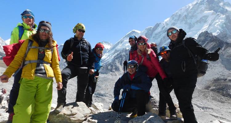 Randonneurs posant avec des montagnes enneigées en arrière-plan.