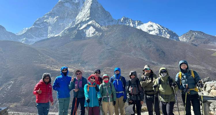 Dix randonneurs debout devant un grand sommet de montagne.