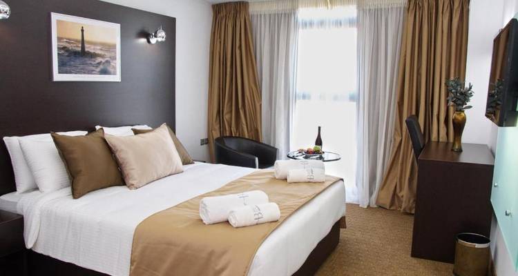 Chambre d'hôtel avec un lit double, une table et un fauteuil.