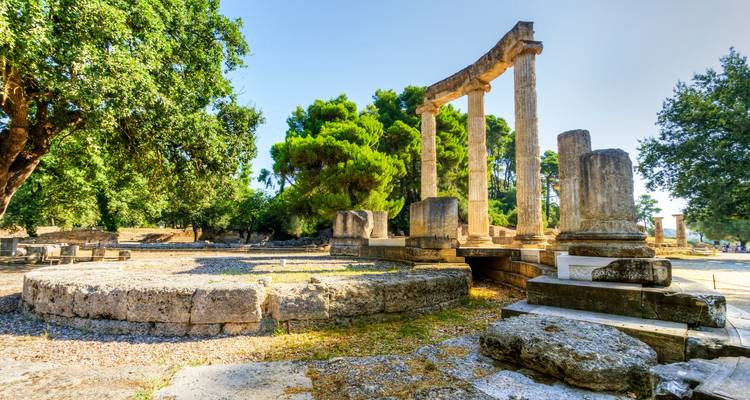 Ruines de l'ancienne Olympie, encadrées par des arbres.