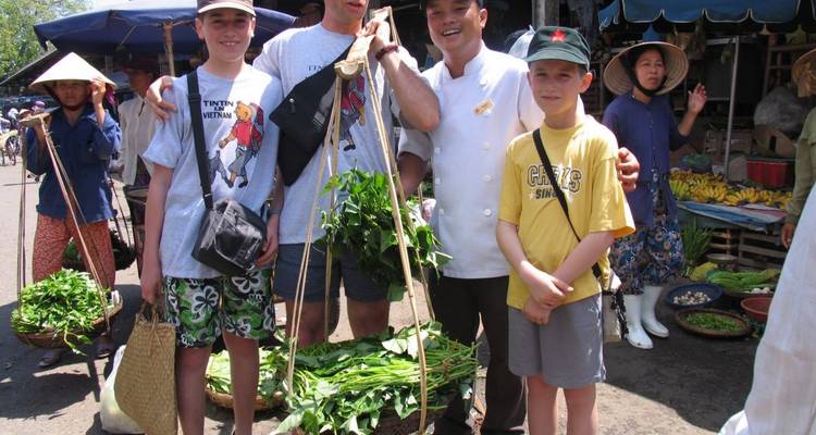 Quatre personnes posant avec des paniers de légumes verts dans un cadre de marché.