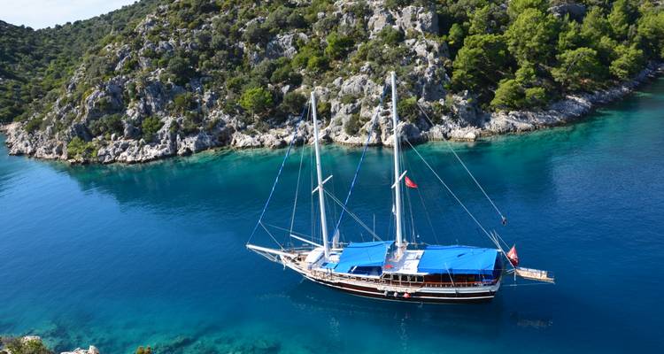 Un bateau sur une eau turquoise claire près d'un rivage rocheux.