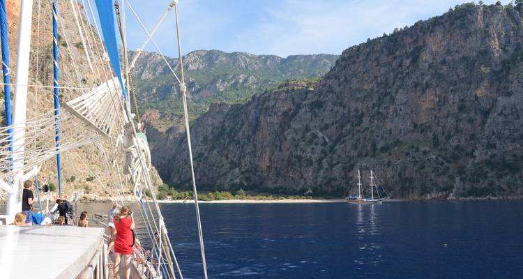 Des gens sur un bateau naviguant près d'une côte rocheuse.