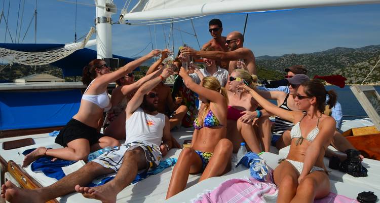 Groupe de personnes trinquant avec leurs boissons sur un bateau.