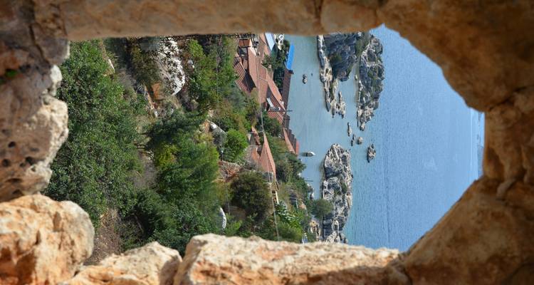 Vue à travers une fenêtre en pierre vers la baie avec des îles rocheuses.