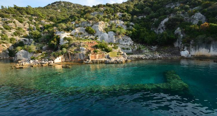 Ruines et eau claire dans un cadre côtier rocheux.