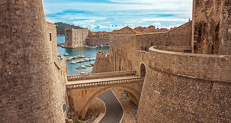 Muros de piedra históricos y vista panorámica del puerto bajo cielos despejados.