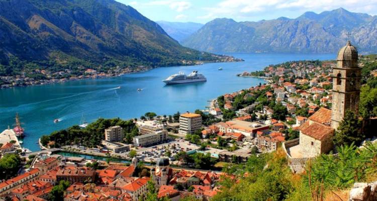 Panoramisch uitzicht op Kotor met een groot cruiseschip in de baai.