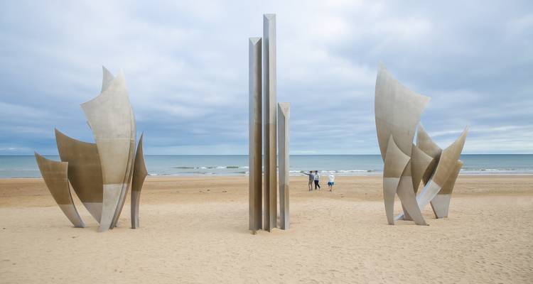 Modern sculpture on a sandy beach with the sea in the background.