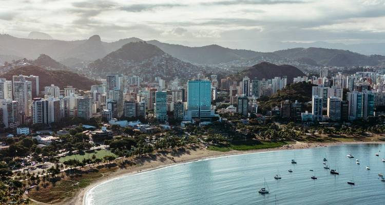 Oceanfront cityscape with high-rise buildings and mountains.