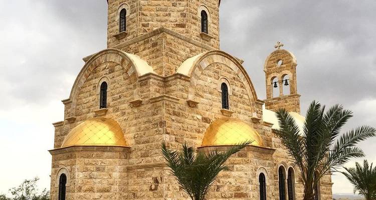 Eine Steinkirche mit goldenen Kuppeln und Palmen.