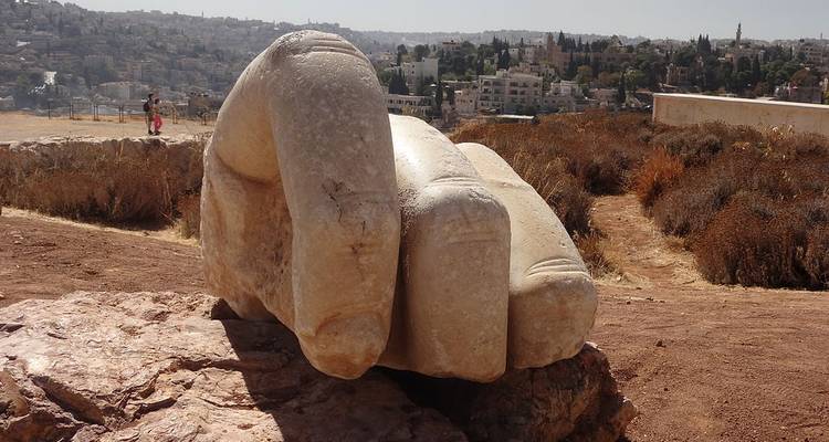 Eine riesige Steinhand-Skulptur mit einer Stadtsilhouette im Hintergrund.