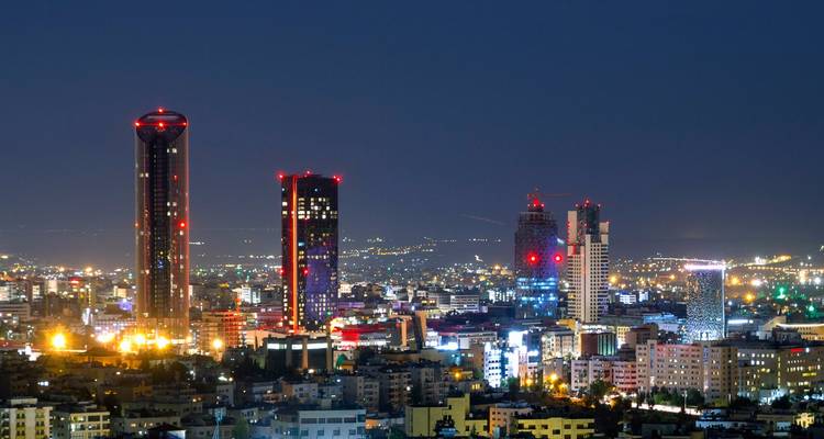 Eine Stadtlandschaft bei Nacht mit hell erleuchteten Wolkenkratzern.