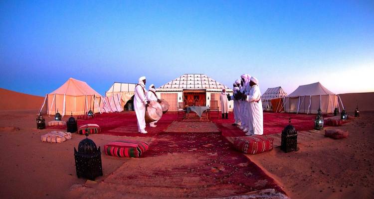 Tentes traditionnelles installées dans un campement du désert au coucher du soleil.