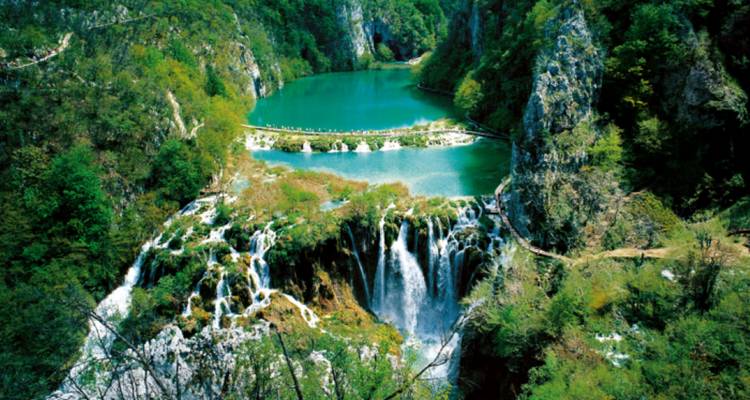 Vue aérienne de cascades et d'un paysage luxuriant se jetant dans un lac limpide.