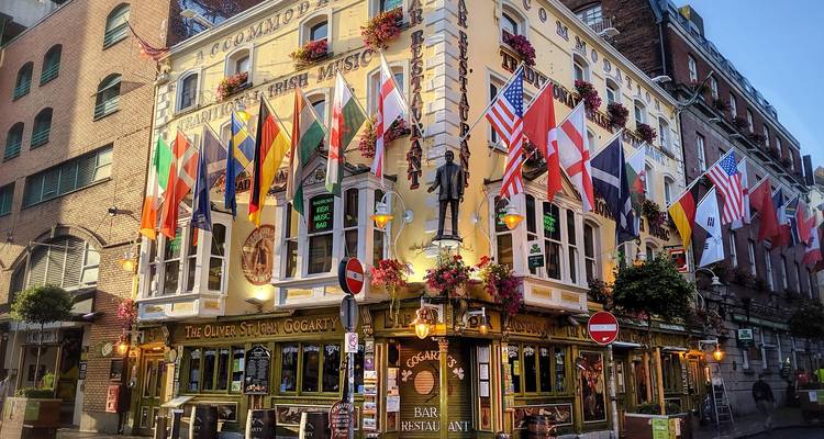 Pub irlandais avec drapeaux et fleurs à un coin de rue animé