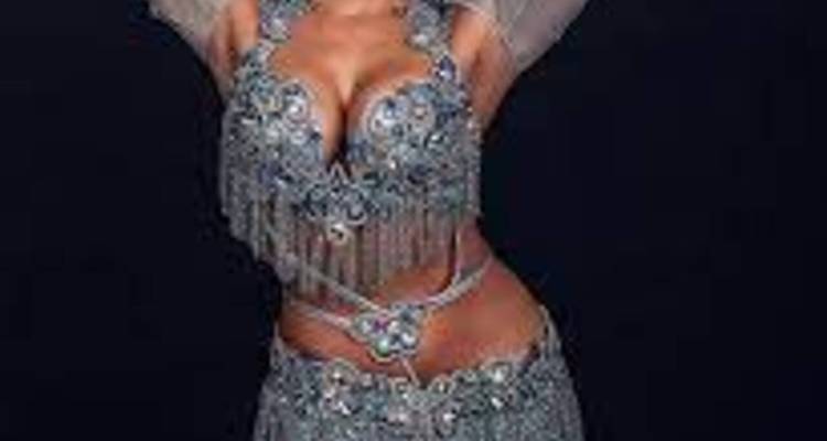 Gros plan d'un artiste costumé dans une tenue scintillante sur fond sombre.