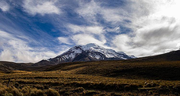 Montaña cubierta de nieve bajo un cielo parcialmente nublado.