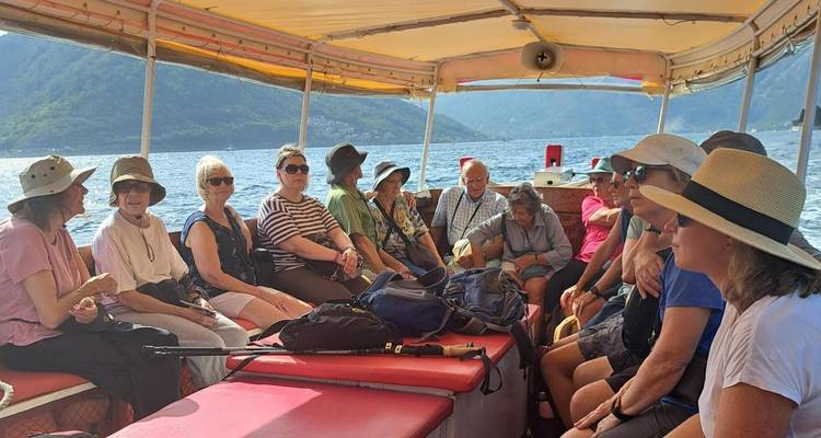 Grupo de turistas sentados dentro de un bote pequeño charlando mientras navegan la Bahía de Kotor