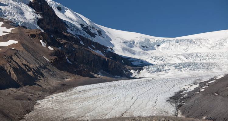 Een uitgestrekte gletsjer die zich uitstrekt tussen rotsachtige bergen.