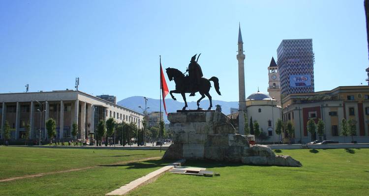 Estatua ecuestre con edificios urbanos y mezquita al fondo.